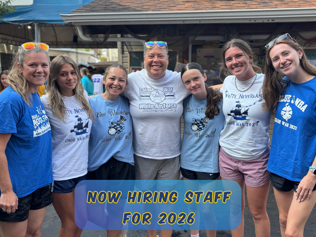 Two camp staff members smiling together on a play structure at Rolling River Day Camp